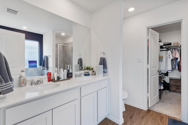 full bath with a shower stall, toilet, visible vents, and a sink