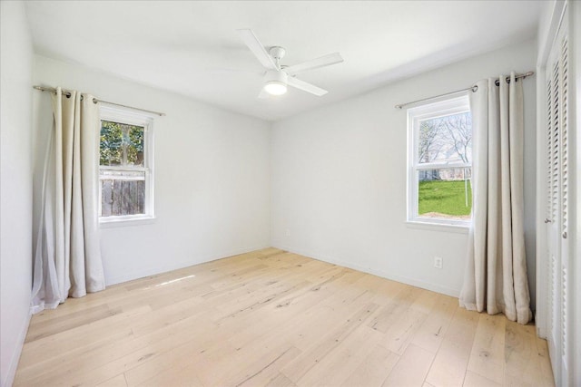 unfurnished room featuring a wealth of natural light, baseboards, ceiling fan, and light wood finished floors