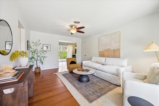 living area with visible vents, baseboards, wood finished floors, and a ceiling fan