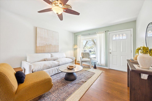 living area featuring baseboards, ceiling fan, and wood finished floors