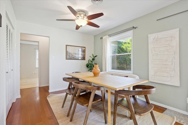 dining room with baseboards, wood finished floors, visible vents, and ceiling fan