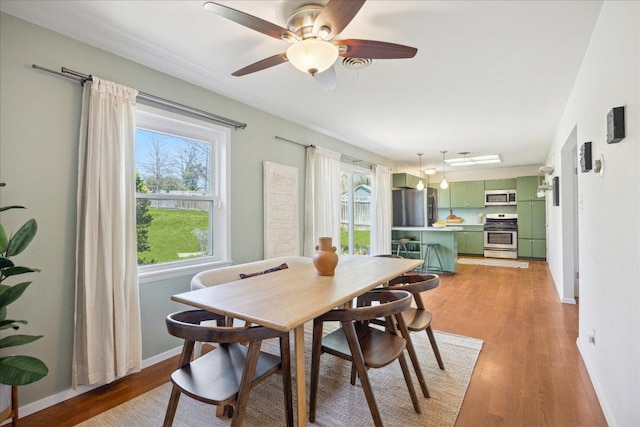 dining area featuring ceiling fan, baseboards, and light wood-style floors