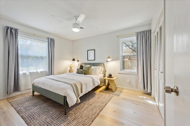 bedroom with baseboards, light wood-type flooring, a closet, and ceiling fan