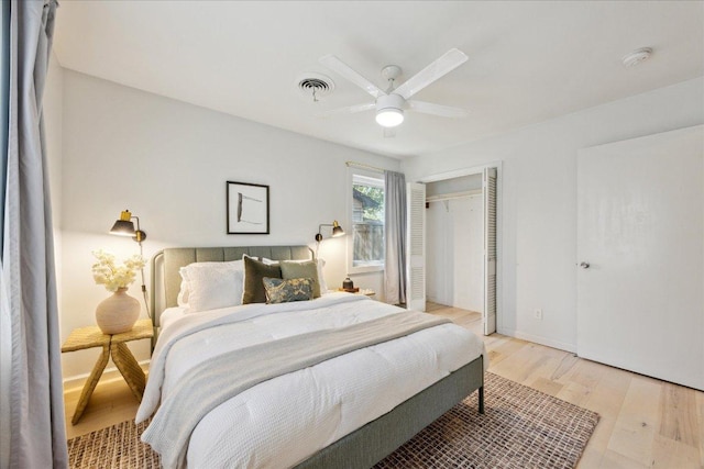 bedroom featuring light wood-type flooring, visible vents, a closet, baseboards, and ceiling fan