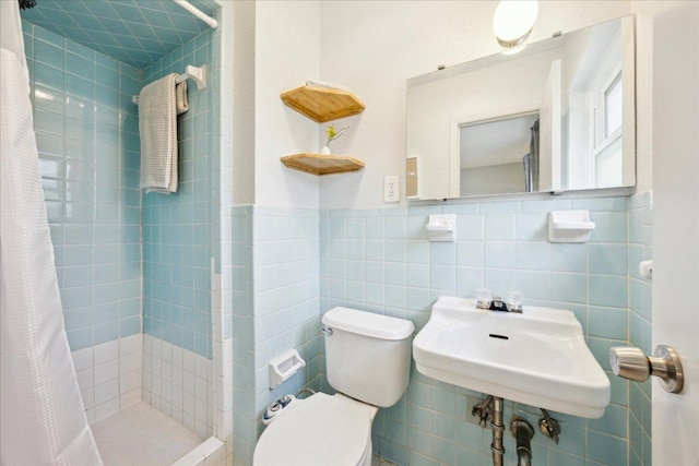 full bath featuring toilet, a sink, tile walls, wainscoting, and a shower stall