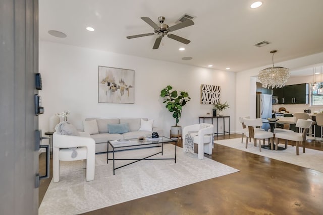 living room with ceiling fan with notable chandelier, recessed lighting, visible vents, and finished concrete floors