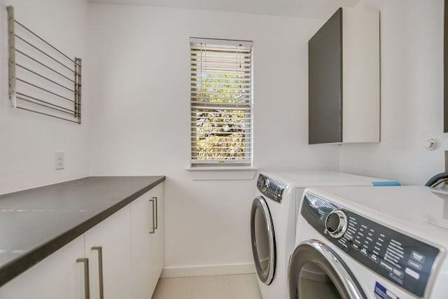 washroom with plenty of natural light, cabinet space, baseboards, and washer and clothes dryer