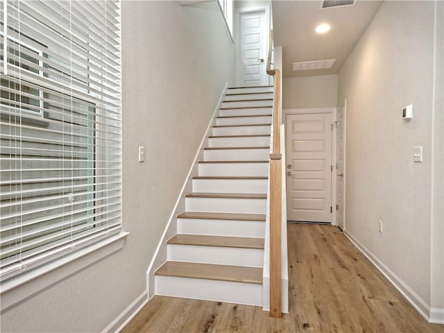 stairs with visible vents, baseboards, and wood finished floors