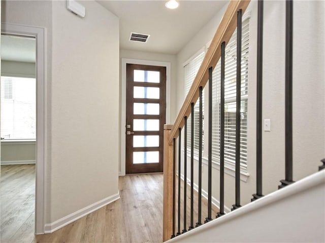 foyer with visible vents, plenty of natural light, baseboards, and wood finished floors