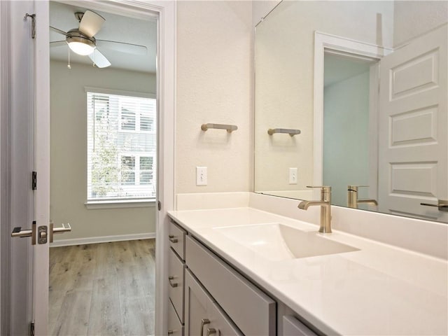 bathroom with ceiling fan, baseboards, wood finished floors, and vanity