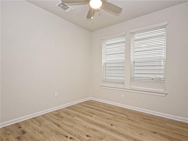 empty room featuring visible vents, a ceiling fan, baseboards, and light wood finished floors