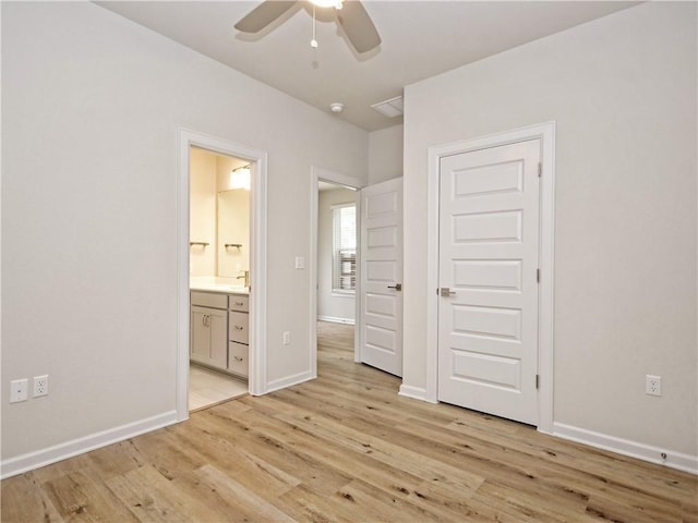 unfurnished bedroom featuring a sink, baseboards, light wood-style flooring, and ensuite bathroom