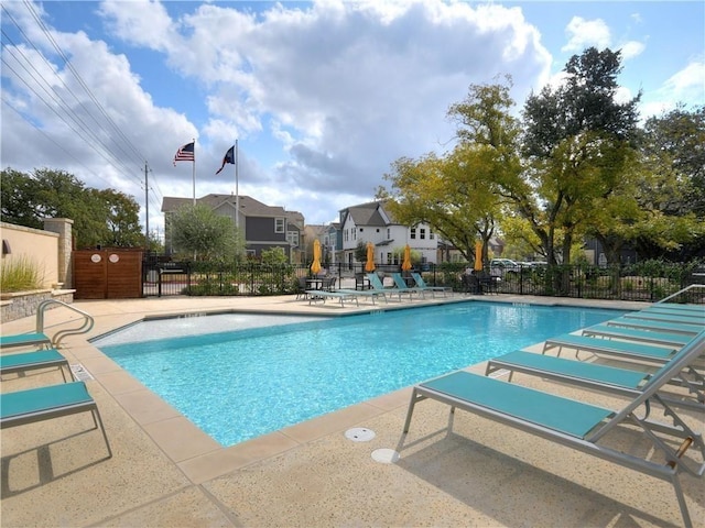 pool with a patio area, fence, and a residential view