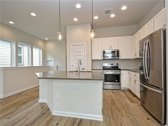 kitchen featuring visible vents, light wood-type flooring, white cabinets, stainless steel appliances, and a sink