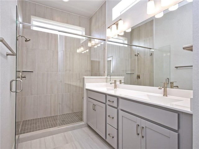 bathroom featuring a sink, a stall shower, and double vanity