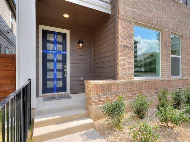 property entrance featuring fence and brick siding