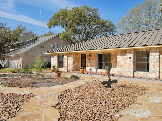 single story home featuring a standing seam roof, stone siding, and metal roof