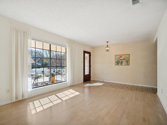 foyer featuring visible vents, baseboards, a textured ceiling, and wood finished floors