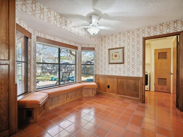 unfurnished room with visible vents, wallpapered walls, washer / clothes dryer, wainscoting, and a textured ceiling