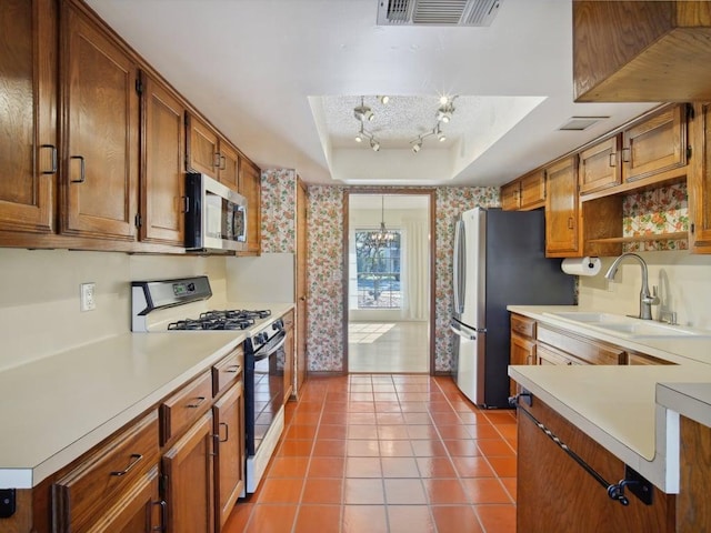 kitchen with visible vents, a sink, appliances with stainless steel finishes, light countertops, and a raised ceiling