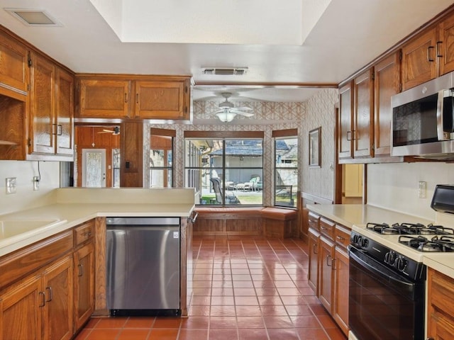 kitchen featuring dark tile patterned floors, stainless steel appliances, wallpapered walls, ceiling fan, and light countertops