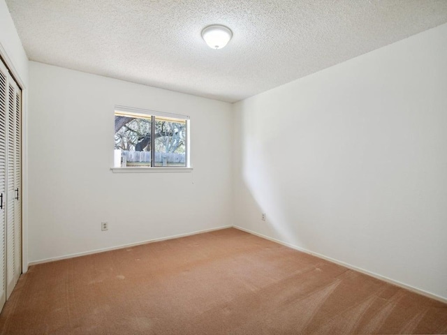 unfurnished bedroom featuring a textured ceiling, baseboards, a closet, and light carpet