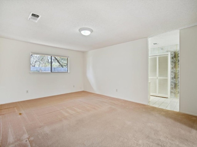 spare room featuring a textured ceiling, visible vents, and light carpet