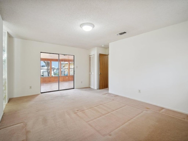 empty room featuring visible vents, baseboards, light colored carpet, and a textured ceiling