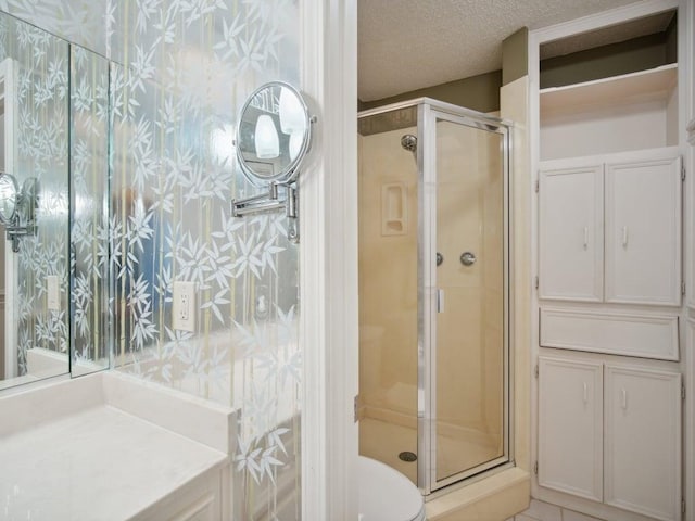 full bathroom with a textured ceiling, a shower stall, and toilet