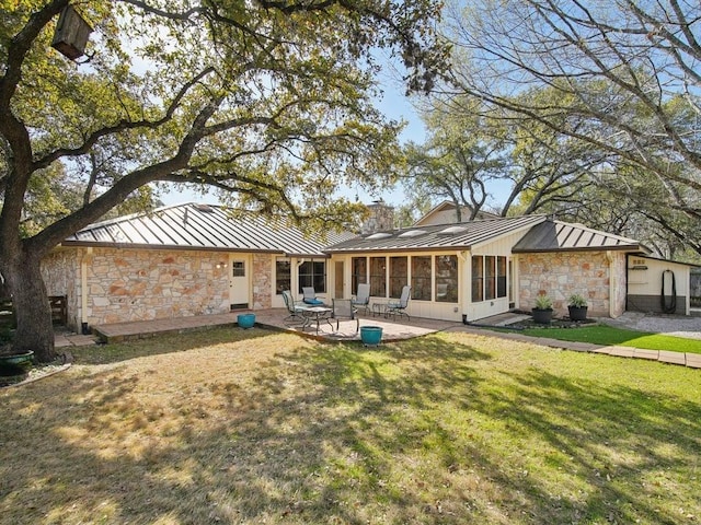 rear view of property featuring a standing seam roof, a patio, stone siding, and metal roof