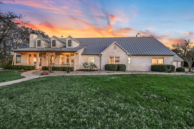 view of front of home featuring metal roof, stone siding, a front yard, and a standing seam roof