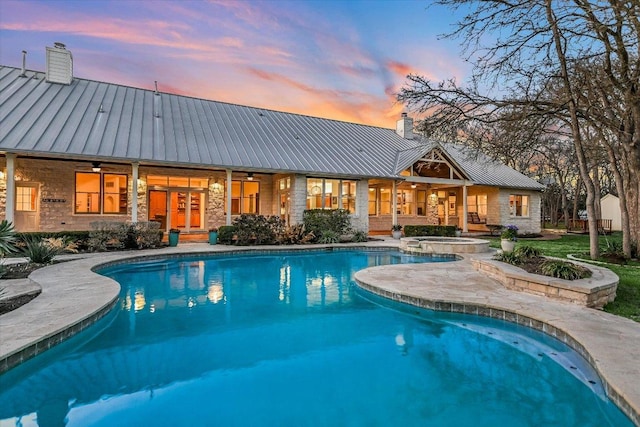 pool at dusk with a patio, a pool with connected hot tub, and a ceiling fan