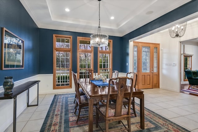 dining space with light tile patterned flooring, a notable chandelier, and a tray ceiling