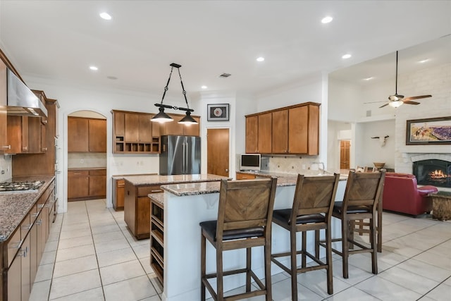 kitchen with brown cabinets, a ceiling fan, tasteful backsplash, appliances with stainless steel finishes, and a peninsula