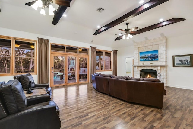 living room featuring a stone fireplace, dark wood-type flooring, visible vents, and ceiling fan