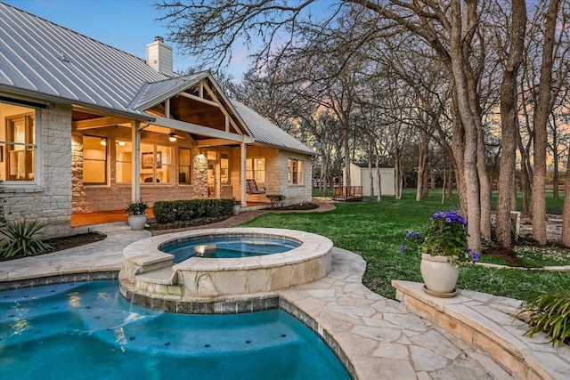 outdoor pool with ceiling fan, an outdoor structure, a yard, an in ground hot tub, and a storage unit