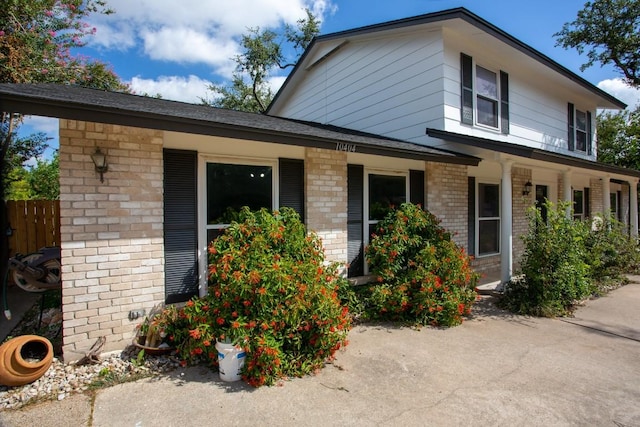 view of front of house featuring fence and brick siding