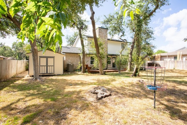 rear view of house featuring a fenced backyard, central AC unit, a storage unit, and an outdoor structure