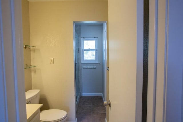 full bath featuring tile patterned floors, toilet, a shower with door, baseboards, and vanity