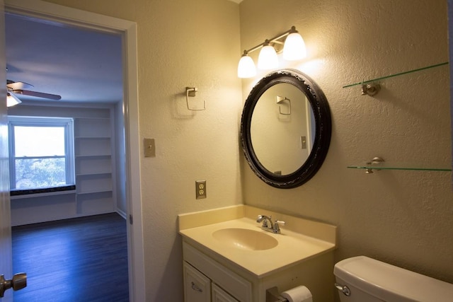 bathroom featuring vanity, wood finished floors, a ceiling fan, toilet, and a textured wall