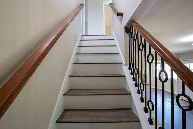 stairs with wood finished floors and a textured wall