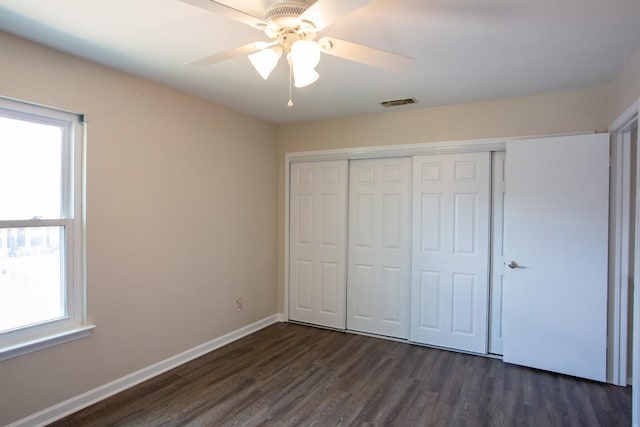 unfurnished bedroom with a ceiling fan, baseboards, visible vents, dark wood-type flooring, and a closet