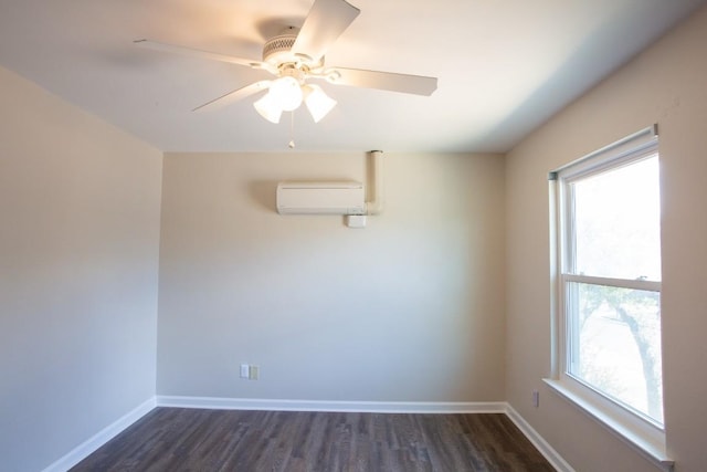 spare room with a wall unit AC, dark wood-style floors, and a healthy amount of sunlight