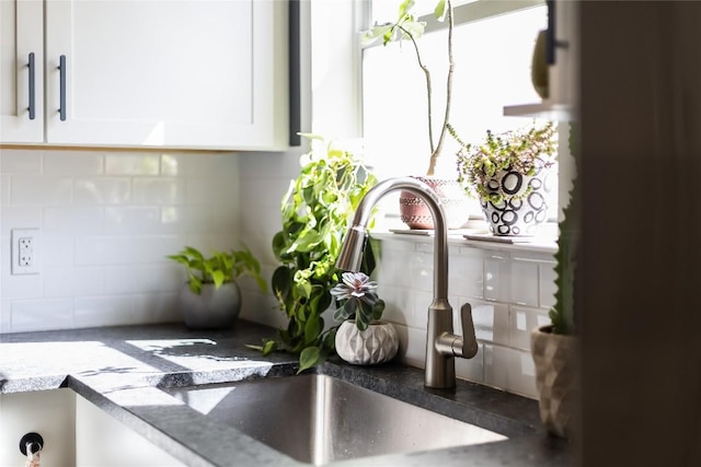 room details with white cabinets, tasteful backsplash, and a sink