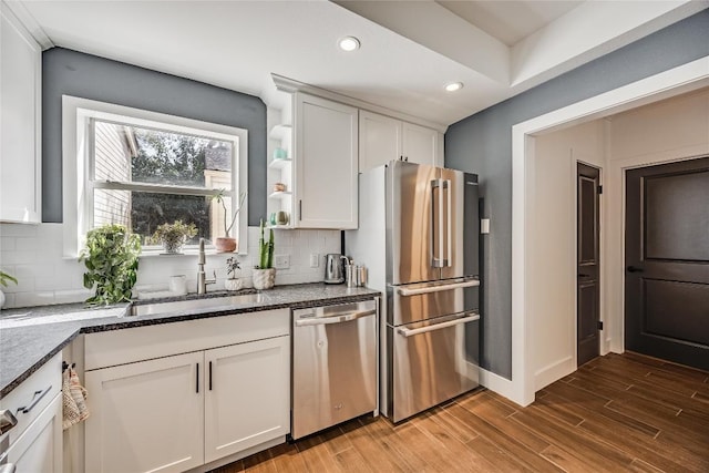 kitchen featuring white cabinetry, wood finished floors, backsplash, and stainless steel appliances