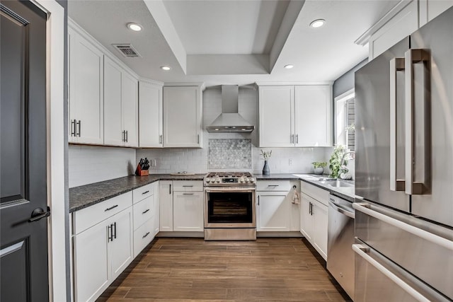 kitchen featuring visible vents, dark wood finished floors, white cabinetry, stainless steel appliances, and wall chimney range hood