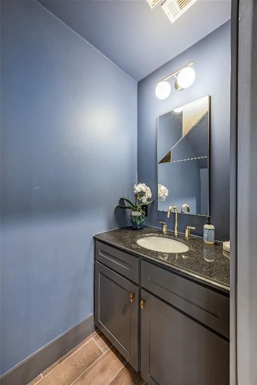 bathroom with visible vents, baseboards, wood finished floors, and vanity