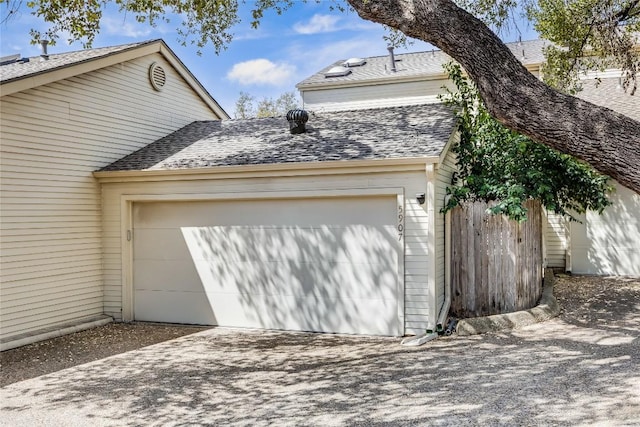 garage with concrete driveway and fence