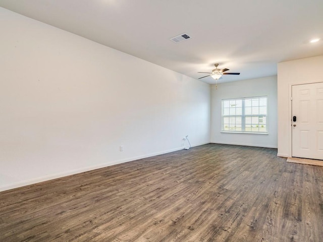 spare room with visible vents, baseboards, dark wood-style floors, and a ceiling fan