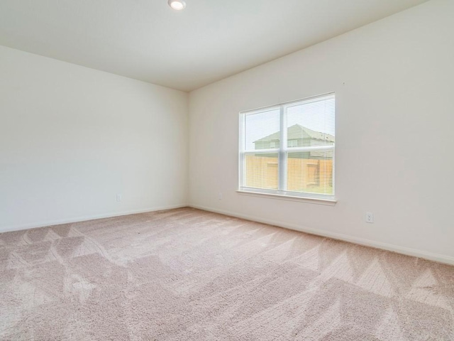 spare room featuring carpet and baseboards